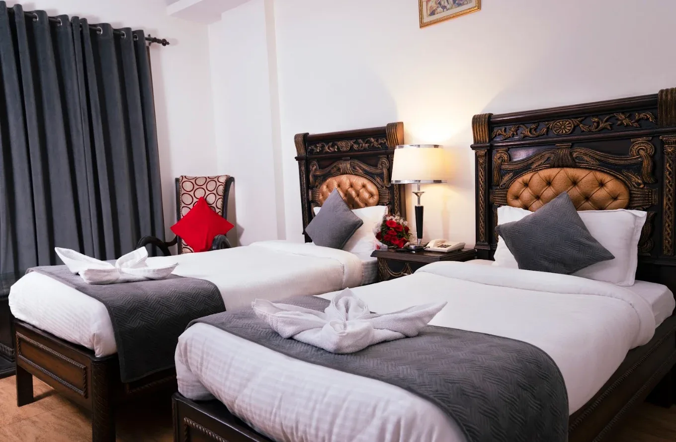 Twin room with hand-carved wooden headboards and brass-toned upholstery