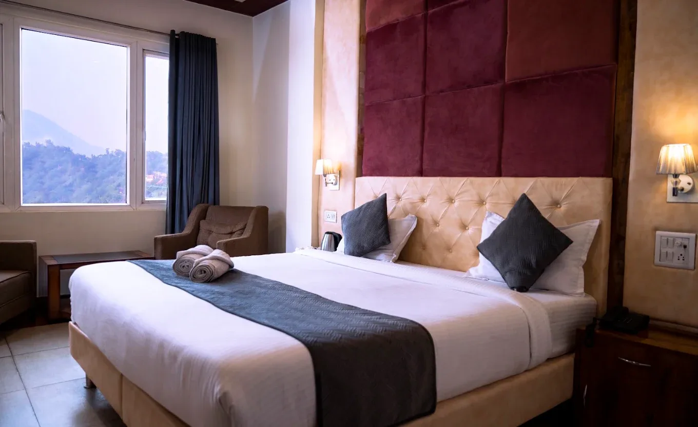 Guest room with a velvet upholstered headboard and a window onto the hills