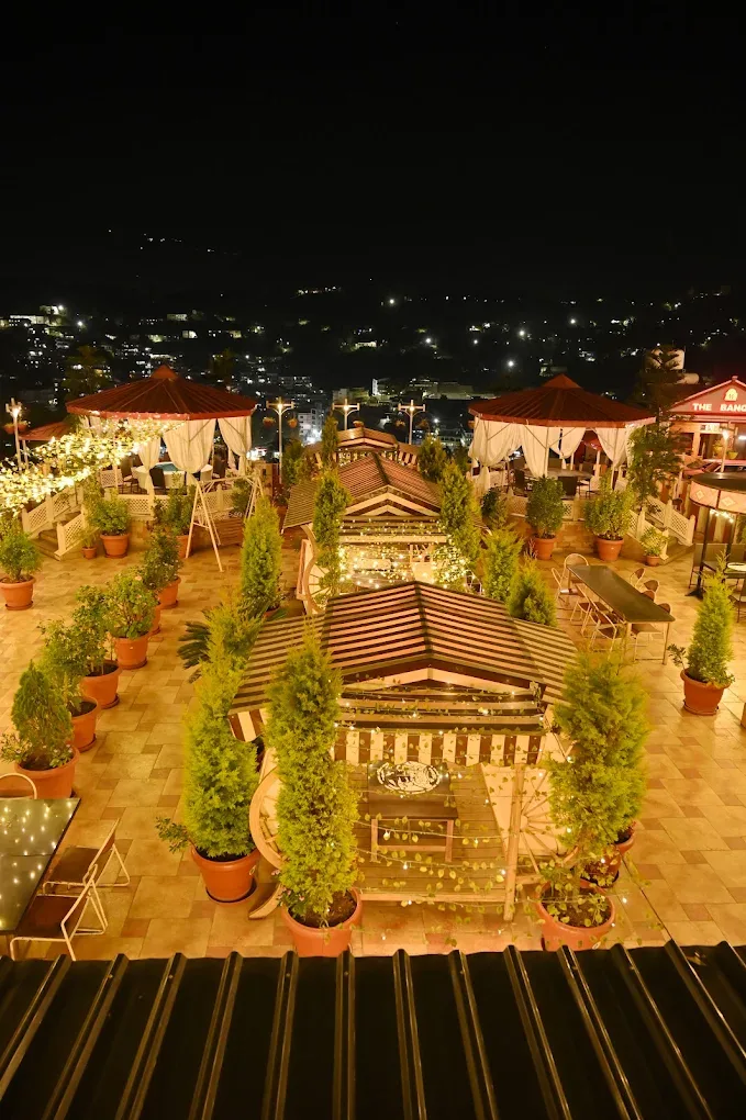 Jannat Terrace seen from above at night, gazebos ringed by potted cypress