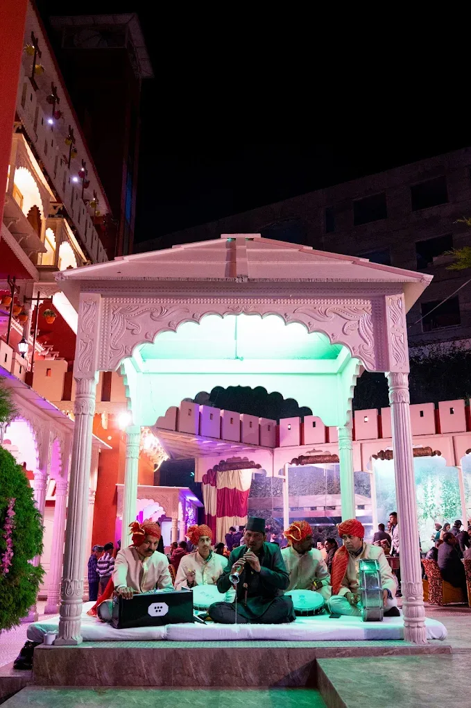 Shehnai and dhol players seated in the carved white gazebo during a wedding
